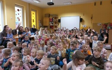 przedszkolaki siedzą i machają rękami