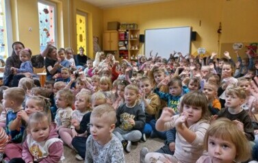 przedszkolaki siedzą i oglądają audycję