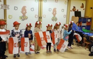 dzieci w biało-czerwonych czapkach i z flagami Polski
