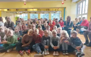 dzieci z grupy 6 i 7 siedzą na sali gimnastycznej w szkole