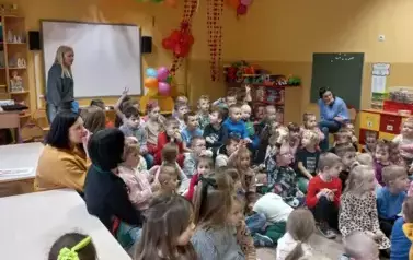 dzieci siedzą i słuchają pogadanki strażaka