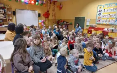 dzieci siedzą i słuchają strażaka
