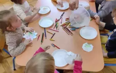 dzieci kładą kwiaty na talerzykach z wodą
