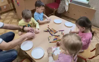 dzieci kładą kwiaty na talerzykach z wodą