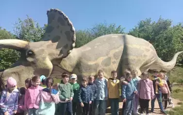 dzieci pozują do zdjęcia przy dinozaurze