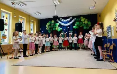 dzieci stoją w p&oacute;łkolu na sali