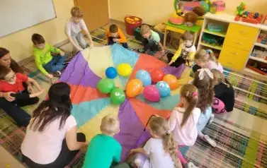 dzieci bawią się balonami i chustą animacyjną