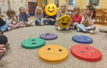 dzieci siedzą w kole, na środku leżą symbole emocji