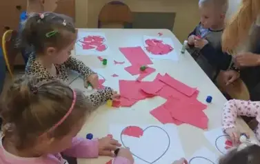 dzieci wyklejają serce czerwonym papierem