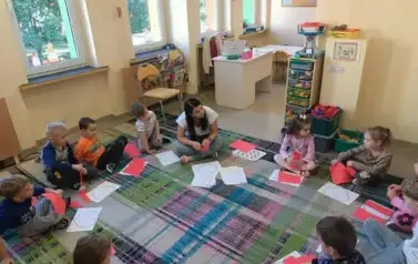 dzieci siedzą w kole z nauczycielką