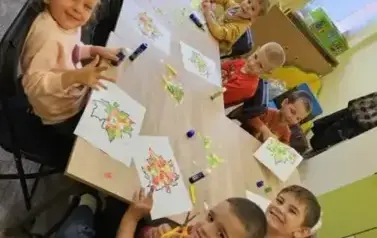 dzieci wyklejają liście kolorowym papierem
