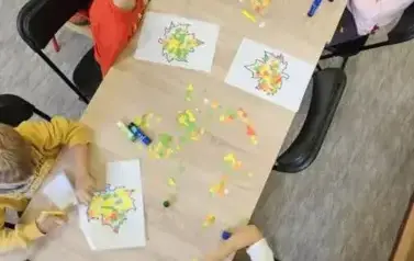 dzieci wyklejają liście kolorowym papierem