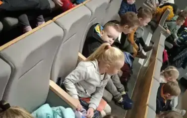 dzieci siedzą na krzesełkach w kinie