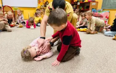 chłopiec układa dziewczynkę w pozycji bocznej bezpiecznej