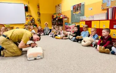 strażak pokazuje na fantomie jak sprawdzić czy nieprzytomna osoba oddycha