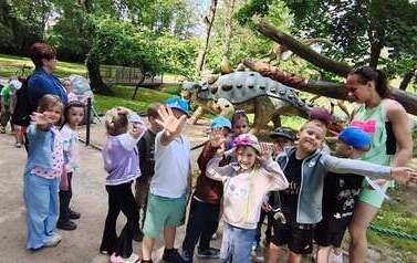dzieci zwiedzają park dinozaur&oacute;w