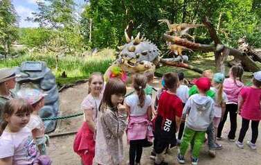 dzieci zwiedzają park dinozaur&oacute;w