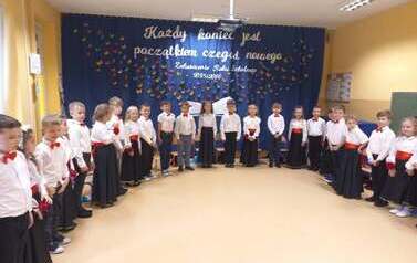 dzieci ustawione w płkolu na tle dekoracji
