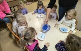 pani nalewa płynu do miseczek, dzieci obserwują