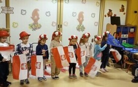 dzieci w biało-czerwonych czapkach i z flagami Polski