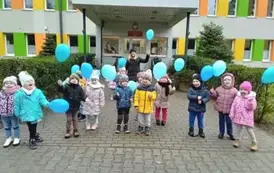 dzieci z grupy 4 przed przedszkolem z niebieskimi balonami