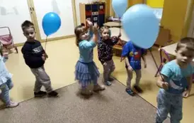 dzieci idą po kole z niebieskimi balonami