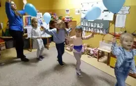 dzieci idą po kole z niebieskimi balonami