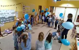 dzieci stoją w kole z niebieskimi balonami