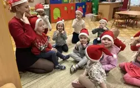 dzieci ubrane mikołajkową siedzą z panią
