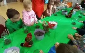 dzieci siedzą przy stolikach z materiałem przyrodniczym