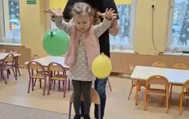 dziecko stoi na krześle z balonami