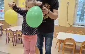 dziecko stoi na krześle z balonami