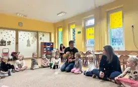 dzieci siedzą w kole z prowadzącym