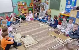 dzieci siedzą w kole z nauczycielem