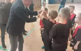 Pan naczelnik wydziału oświaty wręcza dzieciom puchar