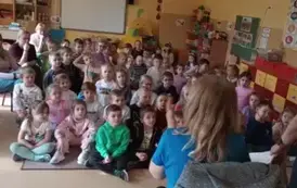 dzieci siedzą i słuchają pogadanki