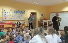 pan prezentuje dzieciom instrument trąbkę 
