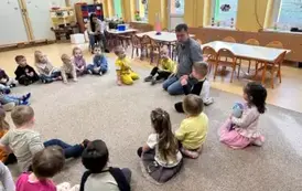 dzieci siedzą w kole z prowadzącym