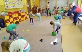 dzieci turlają piłki między pachołkami