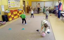 dzieci turlają piłki między pachołkami