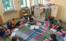 dzieci siedzą w kole z nauczycielką