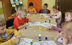 dzieci wyklejają liście kolorowym papierem