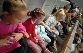 dzieci siedzą na krzesełkach w kinie