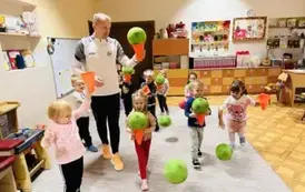 dzieci ćwiczą z piłkami z panem prowadzącym