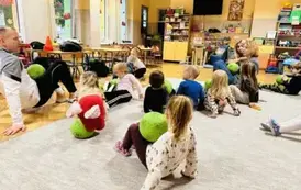 dzieci trzymają piłki na brzuchu