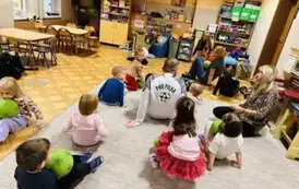 dzieci siedzą z piłkami na dywanie