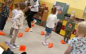 dzieci turlają piłki slalomem