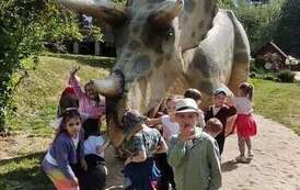 dzieci pozują na tle figury dinozaura