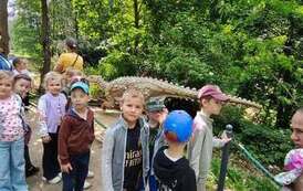 dzieci spacerują po parku dinozaur&oacute;w