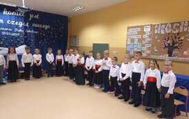 dzieci ustawione w p&oacute;łkolu w uroczystych galowych strojach